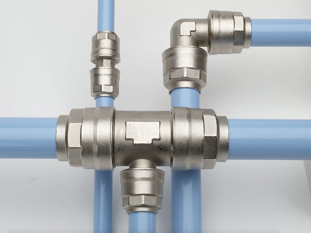 Complex network of metal pipe connectors and blue PVC pipes arranged in an Arle Compressors of Florida configuration on a light background.